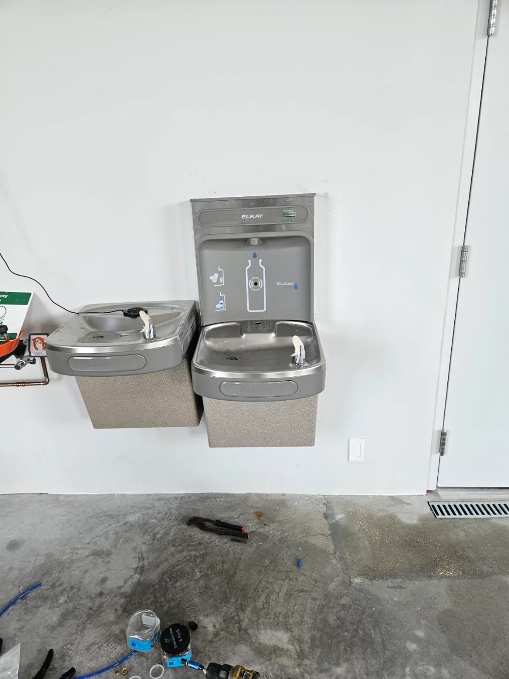 Bi-level drinking fountain with bottle filler installed on a commercial wall