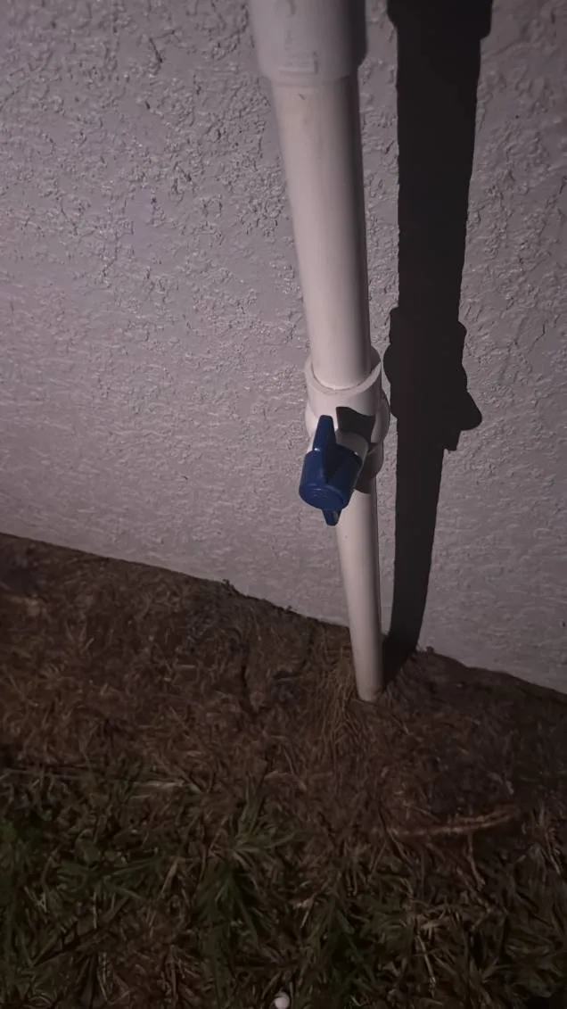 Exterior PVC line with blue-handled ball valve on a stucco wall