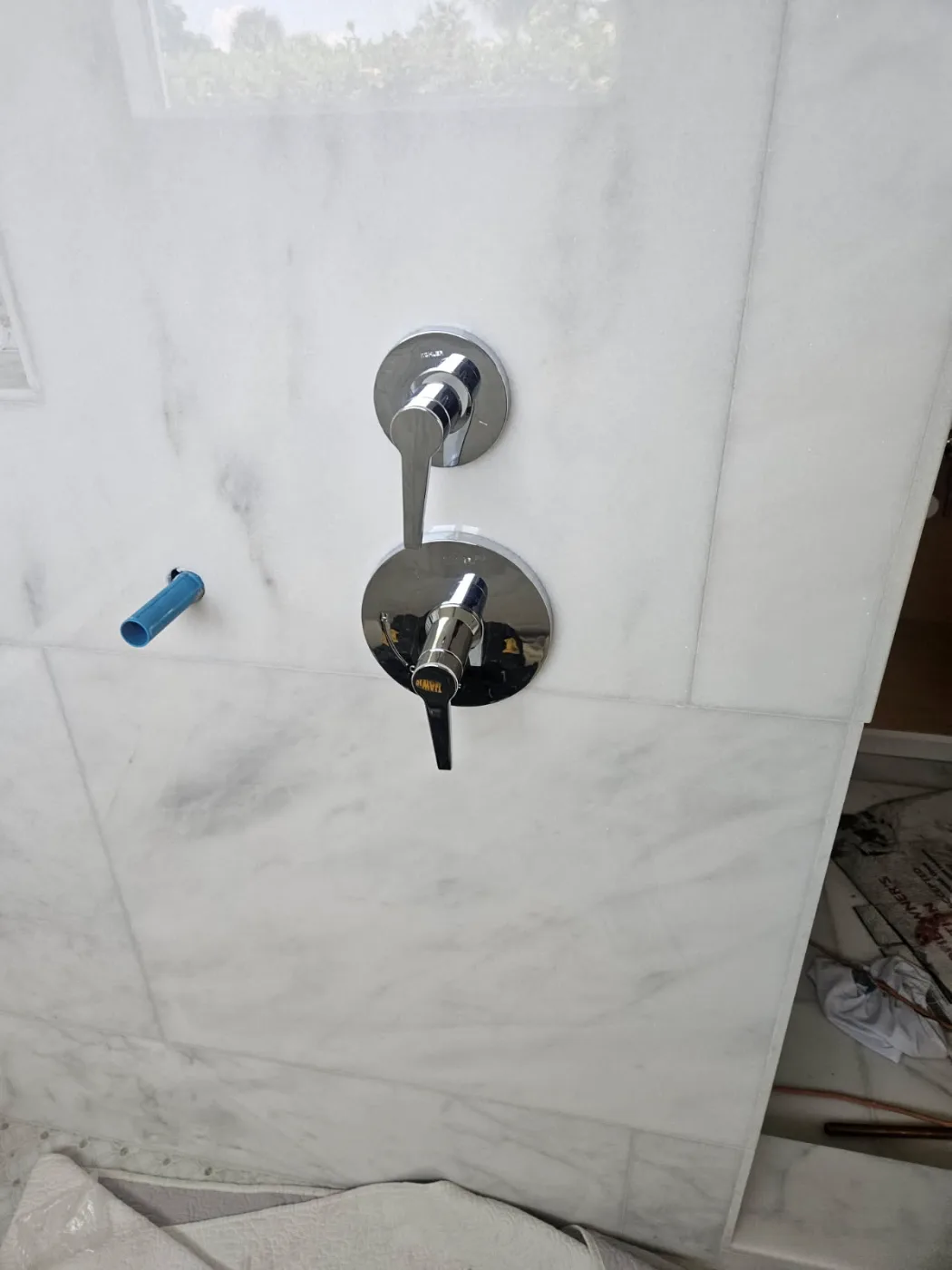 Chrome shower valve and diverter trim installed on marble tile