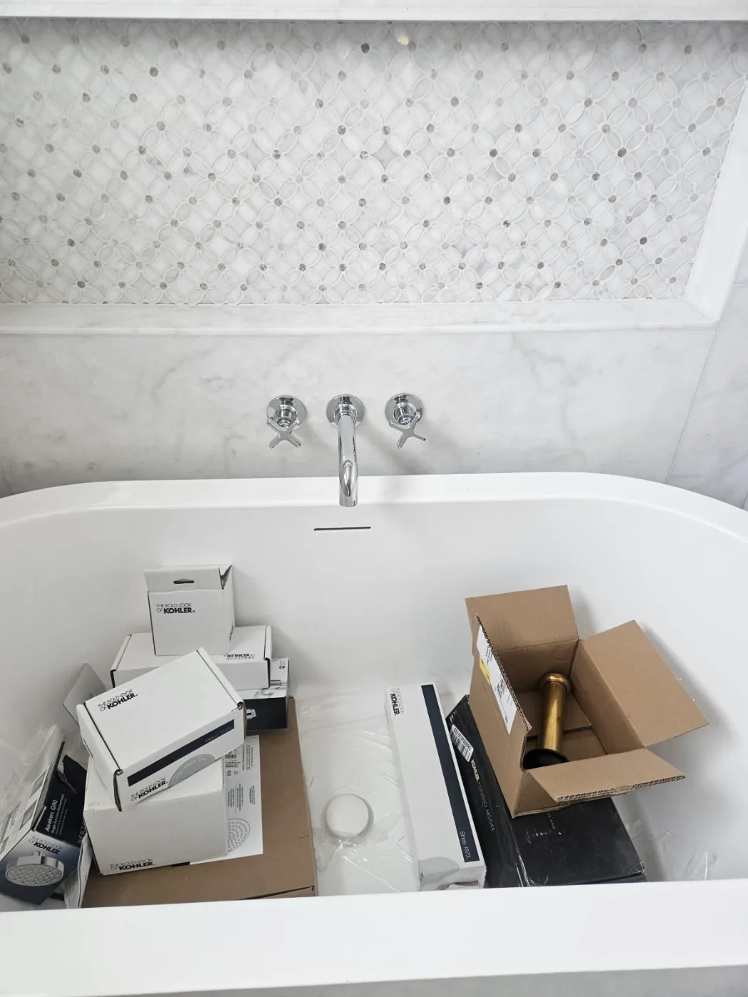 Wall-mount tub filler and cross handles installed above a freestanding tub